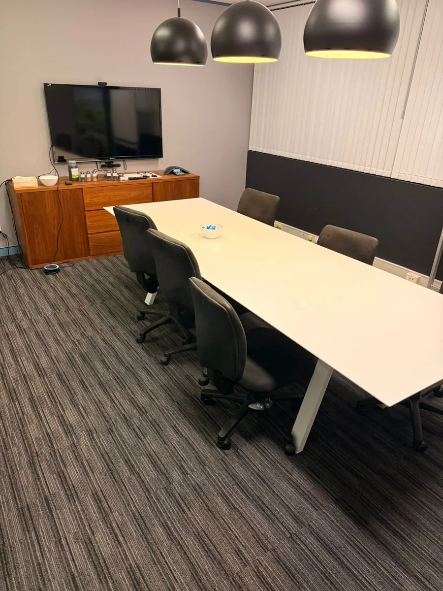 Second meeting room with a long white table, timber sideboard and striped carpet