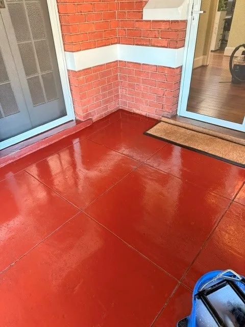 Freshly mopped red tiled office entrance threshold with doormat