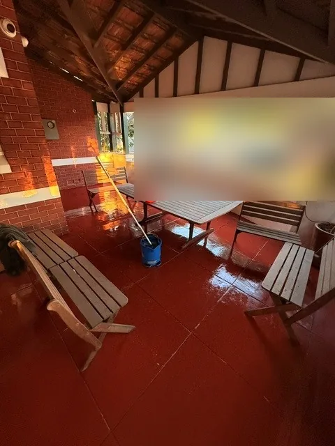 Covered courtyard seating area with table and benches after lifting, scrubbing and mopping