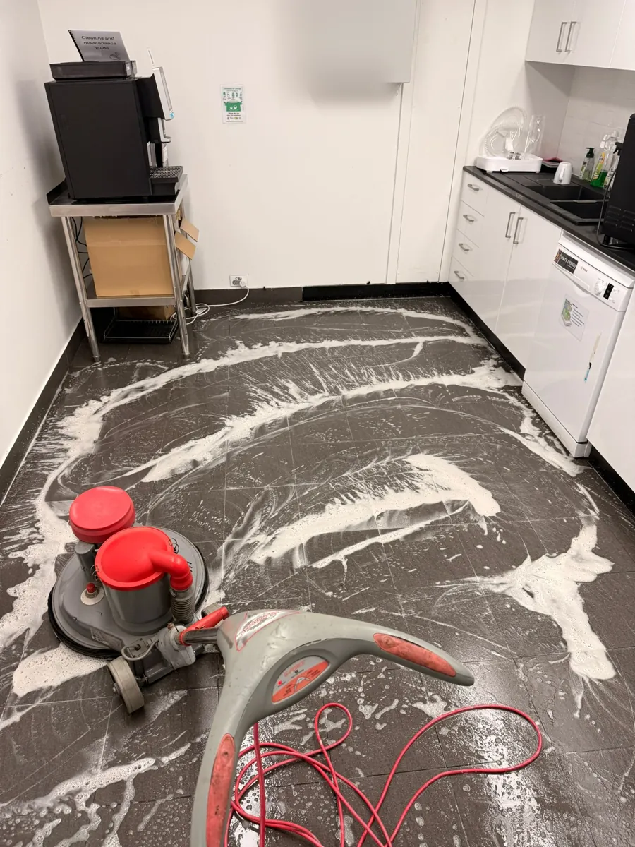 Office kitchen floor tiles being machine scrubbed beside the coffee station