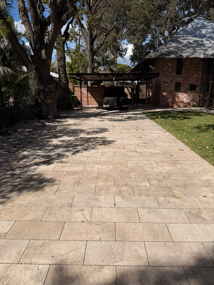 Pale paved driveway after high pressure cleaning, leading to a carport