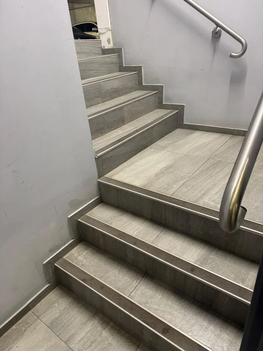 Tiled fire stairwell with stainless handrail after cleaning