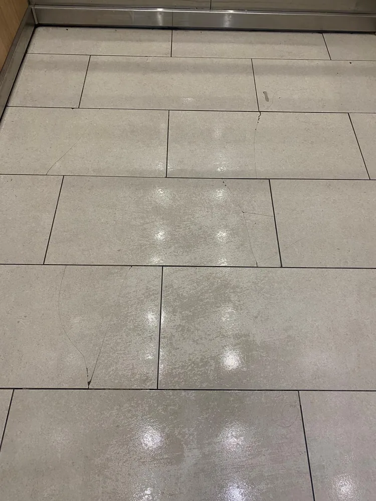 Cracked lift lobby floor tiles photographed during a routine strata inspection