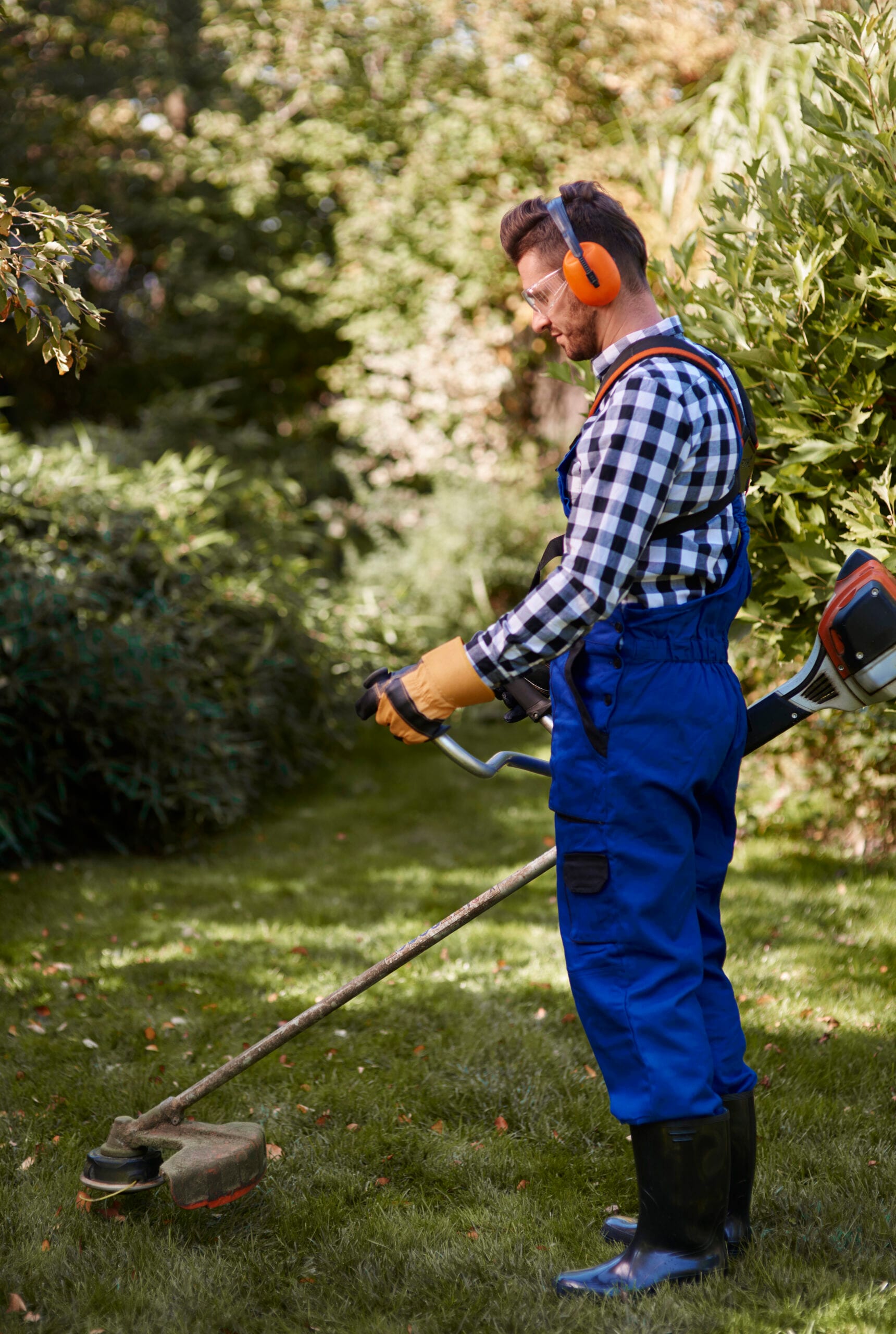 Landscaping specialist inspecting planting beds under integrated property services, ensuring healthy shrubs and soil in strata or commercial grounds.