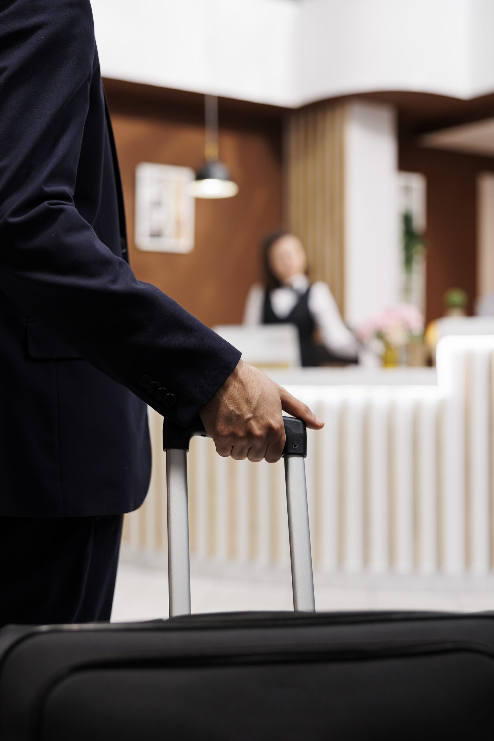 Hotel guest with luggage approaching the front desk to check in