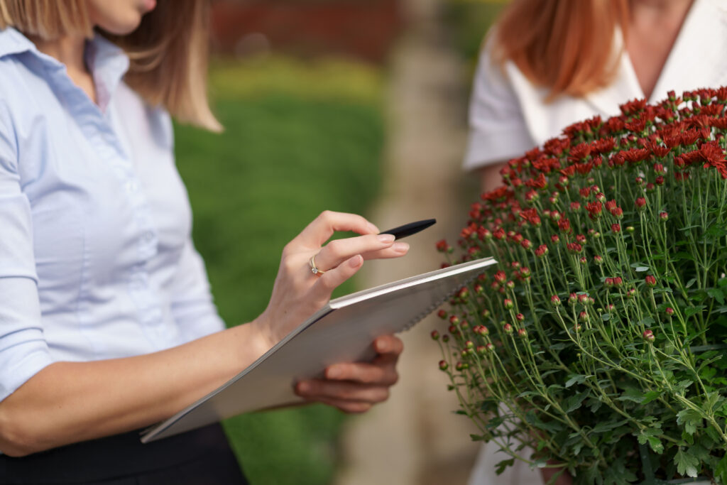 Person drawing a simple backyard layout on paper, marking zones for seating, paths, and plants.